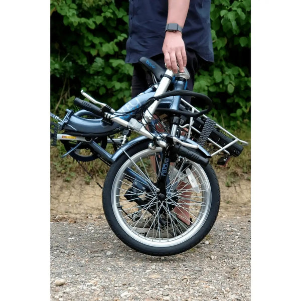 Folded Basis Osprey Low Step Folding Electric Bike 250W being carried by a person, showcasing its portability and compact design.