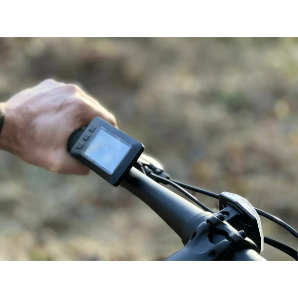 Close-up of the digital handlebar display on the Basis Protocol Electric Hybrid Mountain Bike 250W, showing speed and settings interface.