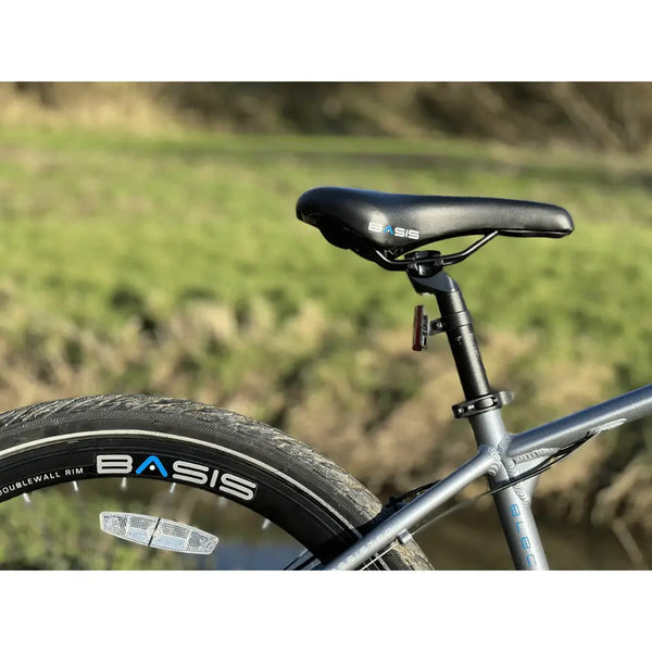Close-up of the Basis Protocol electric bike saddle and rear wheel with double-wall rims and reflective tyre detailing.