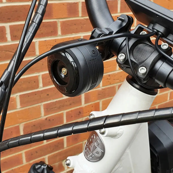 Big Game Bikes 125dB electric bike horn installed on white e-bike handlebar.