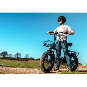 Man standing beside the Big Game Bikes Impala electric bike on a dirt trail, wearing a helmet and ready for off-road riding.