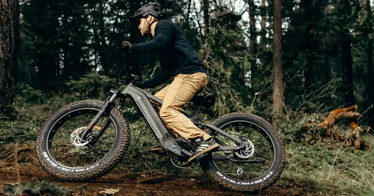 Rider on a fat tyre electric bike navigating a forest trail with wide off-road tyres.