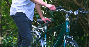 Side view of a man standing with the green Emu Roam crossbar electric bike.