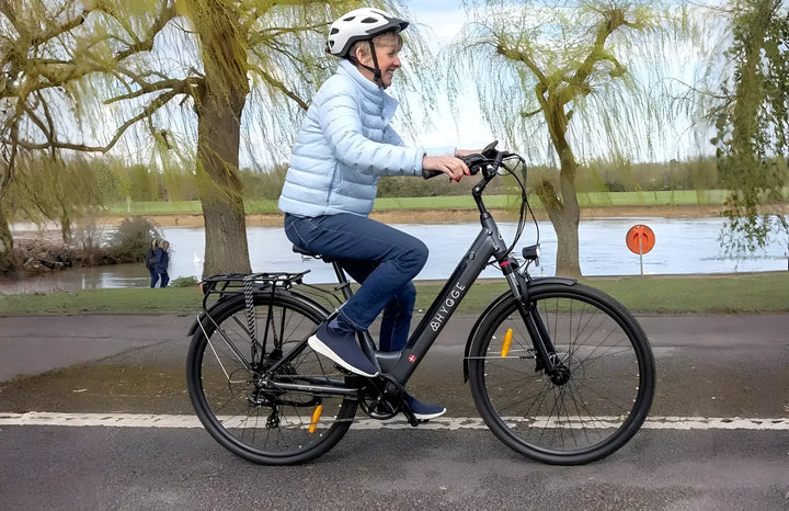 A senior woman enjoying a smooth, upright ride on the Hygge Aarhus step-through electric bike, highlighting the bike’s low-step frame for easy mounting and its comfortable commuter design.