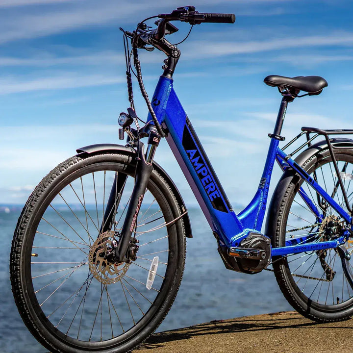Blue Ampere step-through electric bike parked by the coast with sea and sky in the background
