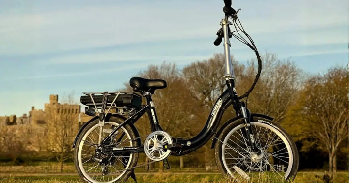 Dallingridge step-through electric bike parked outdoors in a countryside setting with a rear rack and battery mounted above the rear wheel.