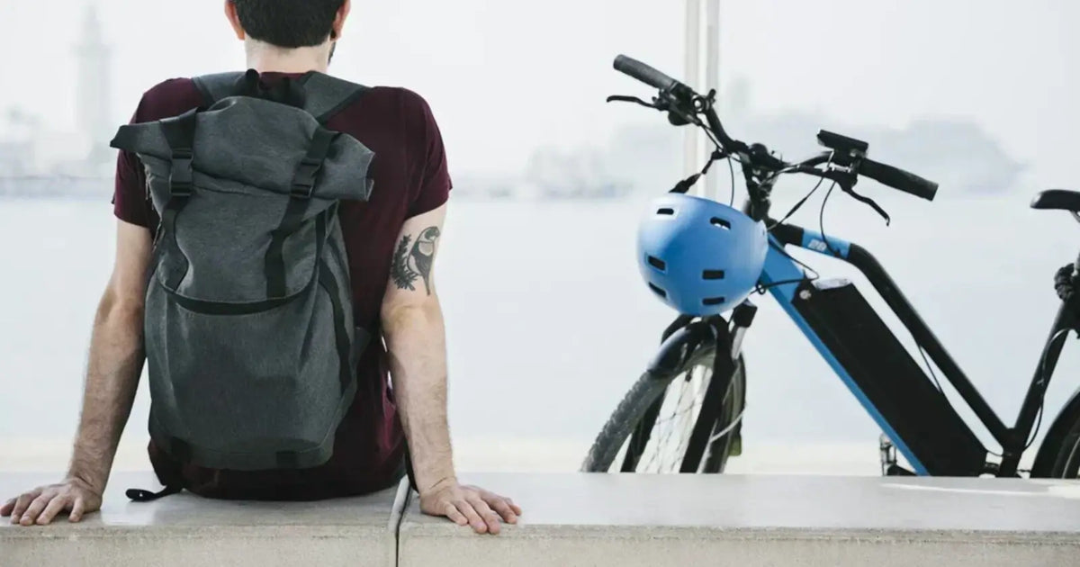 Commuter sitting beside a modern electric bike with helmet and backpack, highlighting the convenience of e-bikes for everyday urban travel.