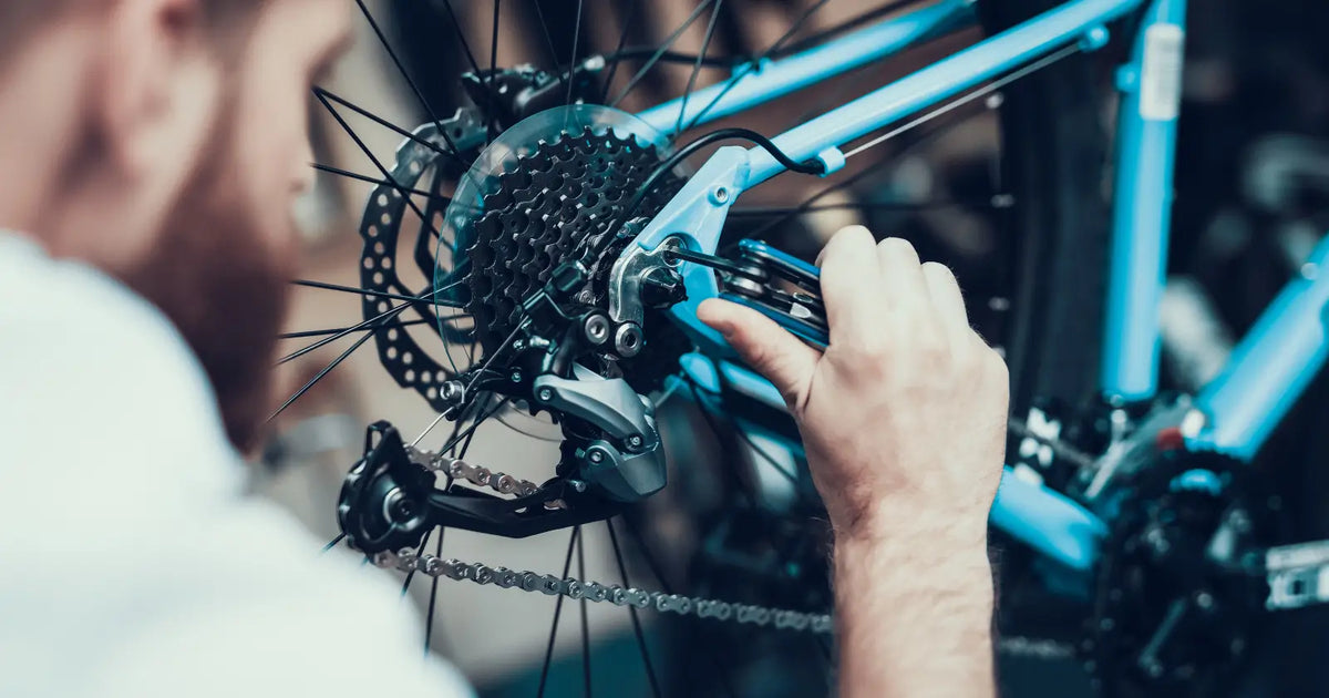 Mechanic adjusting the rear drivetrain and gears of an electric bike during routine repair and maintenance.