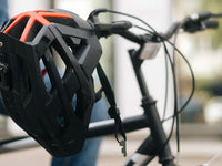 Protective cycling helmet hanging on electric bike handlebars, highlighting essential safety gear for e-bike riders.