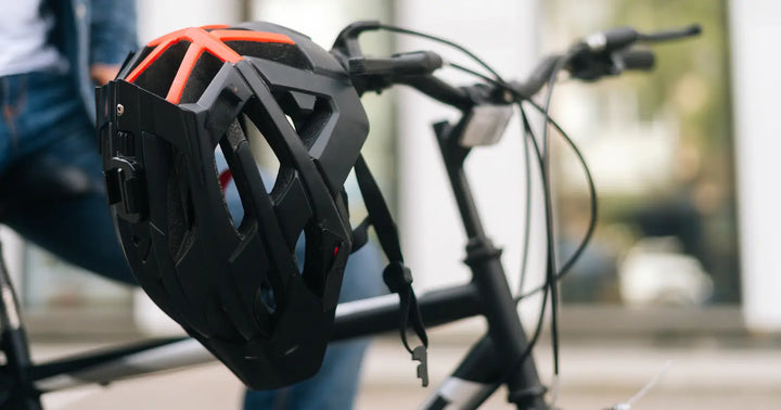 Protective cycling helmet hanging on electric bike handlebars, highlighting essential safety gear for e-bike riders.