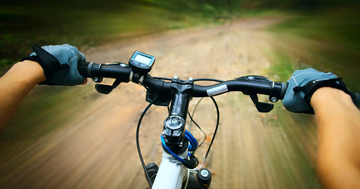 Close-up view of an electric bike throttle control mounted on the handlebar while riding on a trail.