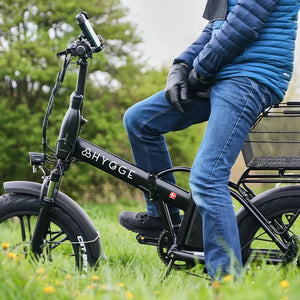 A man sitting on a black electric bike in a park, illustrating a road-legal transport option for individuals who are banned from driving cars.