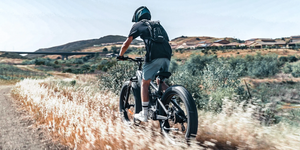 Rider using an electric bike with fat tyres on an off-road trail in a rural landscape