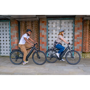 Woman riding a step-through electric bike alongside another rider in an urban setting