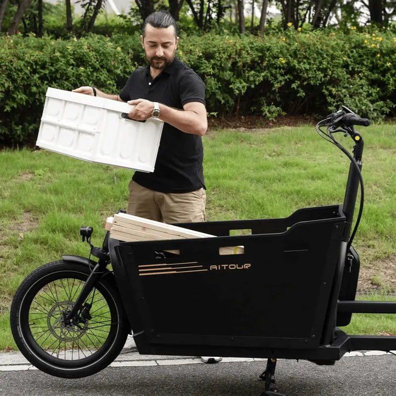 Man placing a large box into the front cargo compartment of the Aitour Basalt electric bike.