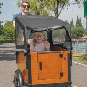 A smiling father pushing the Aitour Family S cargo bike while his daughter waves from inside the weather-protected cargo box equipped with a black rain cover.