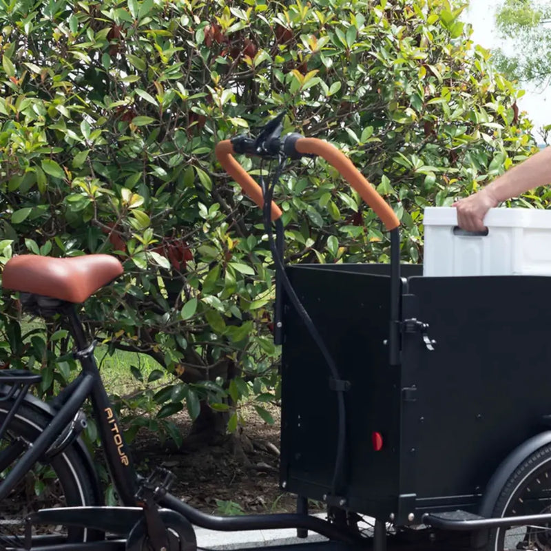 Man loading a white box into the cargo compartment of the Aitour Electric Cargo Bike Starter 250W, built for practical transport and daily use.