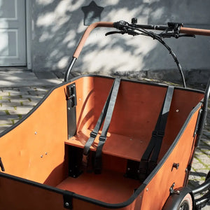 Interior view of the wooden cargo box featuring a bench seat with secure safety belts, designed to safely transport children in the Amcargobikes Ultimate Harmony.