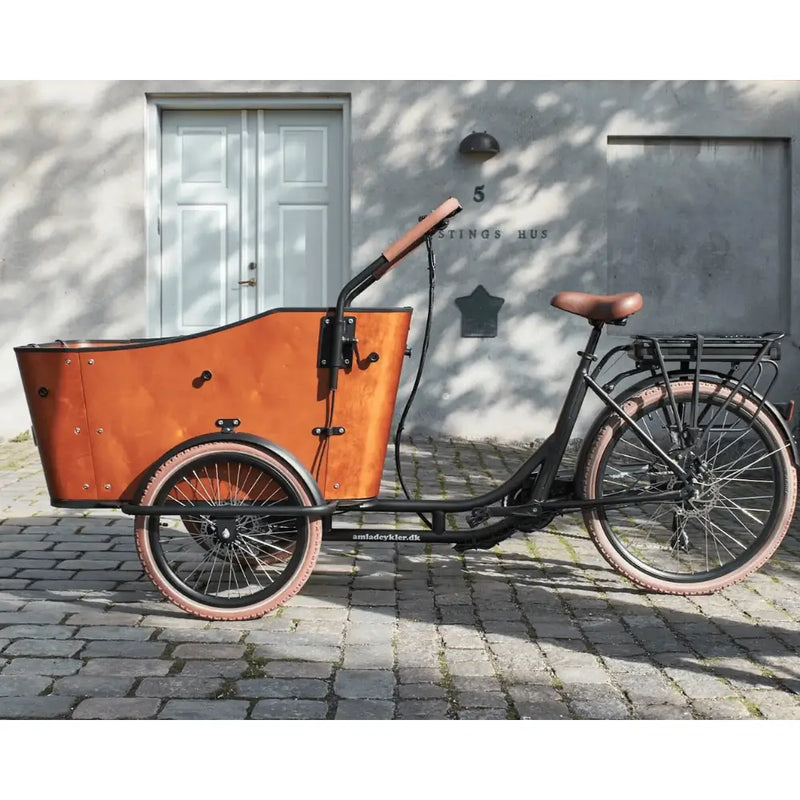 Full side profile of the Ultimate Harmony cargo e-bike, showing the step-through frame design, curved wooden box, and upright seating position suited for family transport.