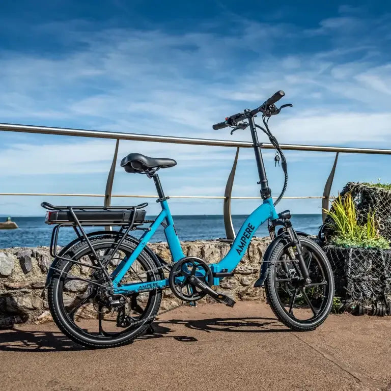 Blue electric bike parked by a railing with a scenic background