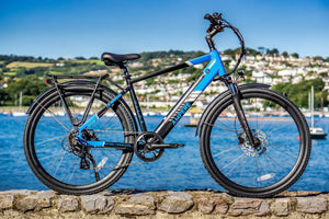 Electric bicycle on a stone wall with a scenic background of water and hills.