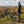 Man standing next to the Ampere X-Trail e-bike in a scenic landscape with rolling hills and a clear sky.