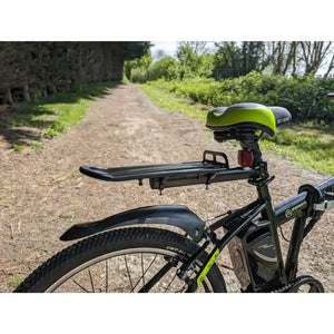 Basis Boxer 24-inch e-bike on a dirt path, showing the padded saddle and seat post-mounted cargo rack.