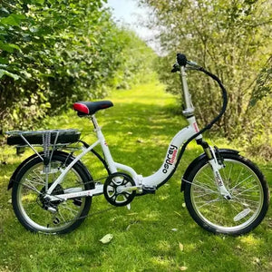 A white folding electric bicycle with black tires and a black saddle, parked on a grassy path surrounded by green trees. The frame features the brand name 'basis osprey' in red and black.