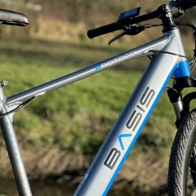 Detail shot of the Basis Protocol Electric Hybrid Mountain Bike 250W frame with visible branding and integrated battery tube.