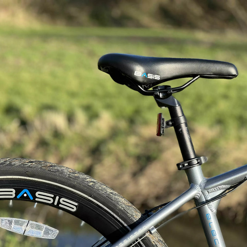 Close-up of the Basis Protocol electric bike saddle and rear wheel with double-wall rims and reflective tyre detailing.