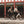 Two riders in helmets cycling a white Batribike Route S and a black Route X past a red timber building