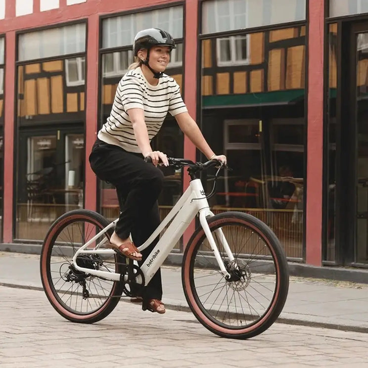 Woman riding the white Batribike Route S electric bike on a city street.