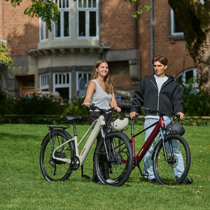 Couple standing on a lawn with an oxblood Batribike SUV X and a cream SUV S
