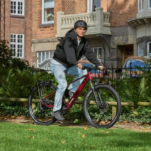 Man in a helmet riding an oxblood Batribike SUV X electric bike along a park path