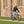 Man riding a grey Batribike Tour X electric bike along a brick path beside a red brick building.