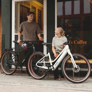 White Batribike Route S electric bikes parked outside a coffee shop with two riders