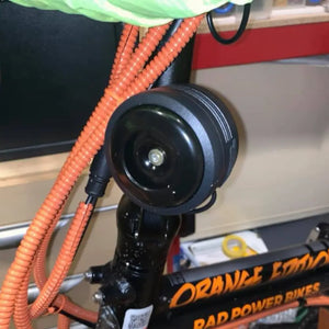 Big Game Bikes 125dB electric bike horn installed on white e-bike handlebar.
