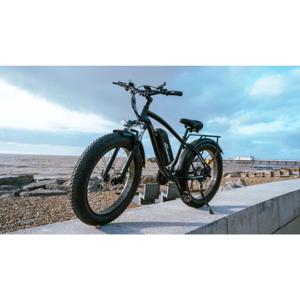 Big Game Bikes Buffalo Mountain electric bike positioned on a seafront ledge with ocean and cloudy sky in the background.