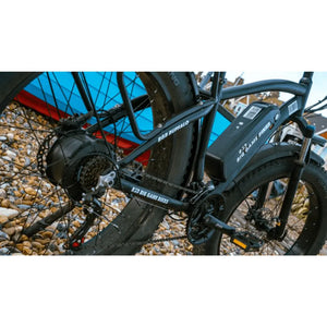 Close-up side view of the Big Game Bikes Buffalo Mountain electric bike showing the drivetrain and battery while parked on rocky terrain.