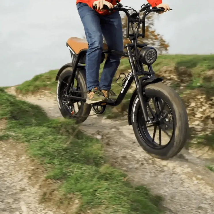 Rider on the Big Game Bikes Warthog Fat Tyre Cruiser Electric Bike going downhill on an off-road trail, highlighting its rugged tyres and cruiser frame.