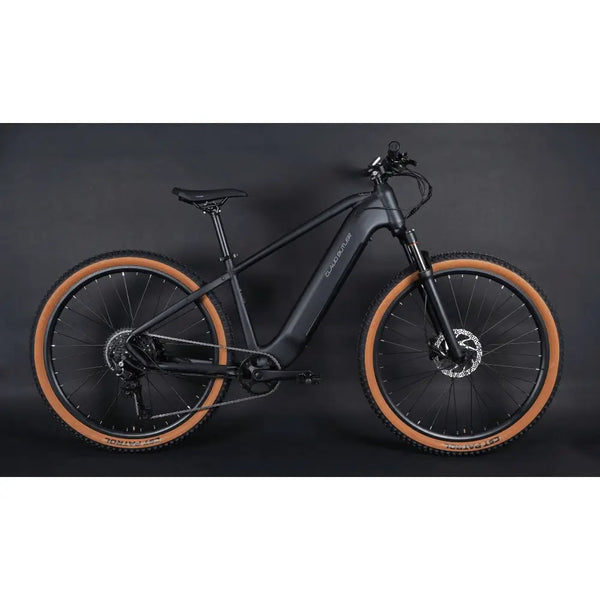 Full side profile of the Claud Butler Wrath 2.0 Cues electric mountain bike, showing the integrated battery, black frame, and tan wall tyres designed for off-road riding.