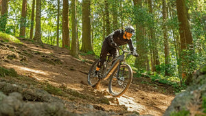 Rider navigating a forest trail on the Claud Butler Wrath 1.0 Cues electric mountain bike, built for off-road performance with 250W motor and robust tyres.
