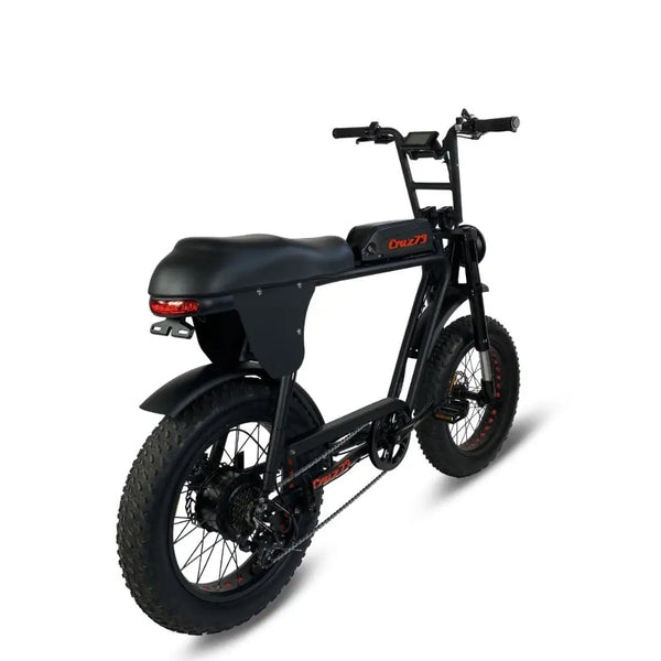 Rear right view of the Cruz73 electric off-road bike in black with wide off-road tyres, chain drive, and integrated rear mudguard.