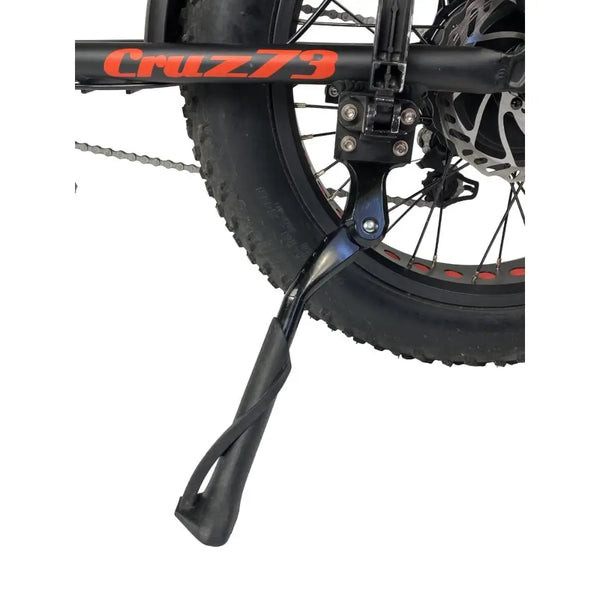 Close-up of the Cruz73 Unlimited Retro Fat Tyre 750W electric bike kickstand attached to the rear wheel frame.