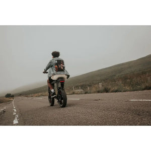 Rear view of a rider on the Cruz73 Unlimited Retro Fat Tyre Electric Bike 750W, cruising along an open countryside road.