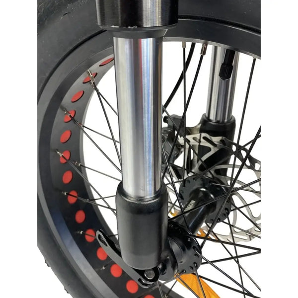 Close-up of the Cruz73 Unlimited Retro Fat Tyre 750W electric bike front suspension forks with wheel spokes.