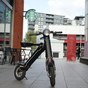 Front view of the black Cruzaa E-Scooter Pro parked outside a coffee shop in a city centre.