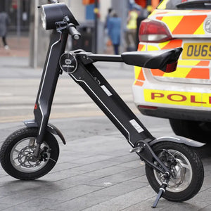 The black Cruzaa E-Scooter Pro parked on a paved high street with an urban background.