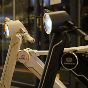 Close-up detail of the powerful LED headlights and branding on both white and black models of the Cruzaa E-Scooter Pro.