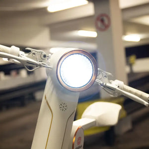 Detail shot of the bright circular LED headlight and handlebars on the white Cruzaa E-Scooter Pro.